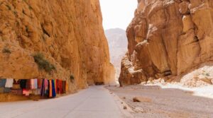 Todra Gorge cliffs with Berber carpets on display near Tinghir