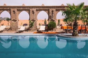 Riad swimming pool with Moorish arches and palm trees in Marrakech