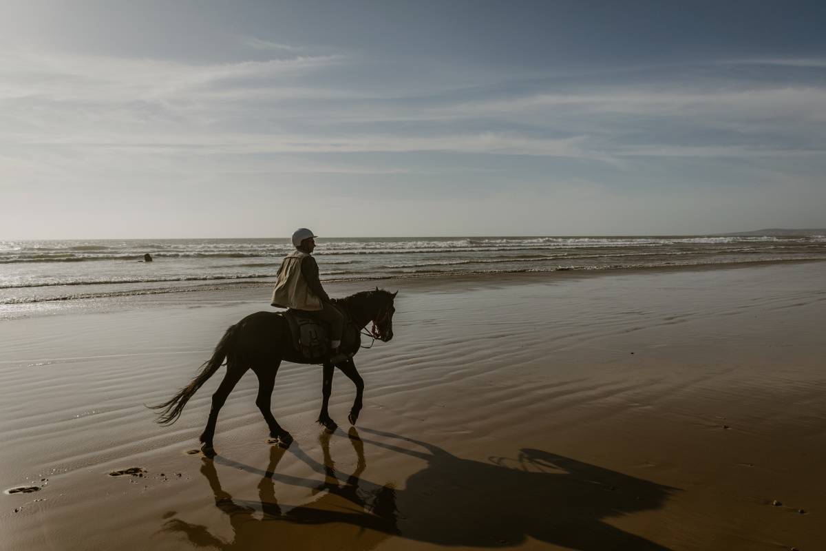 Rider on horseback galloping along Essaouira beach Morocco