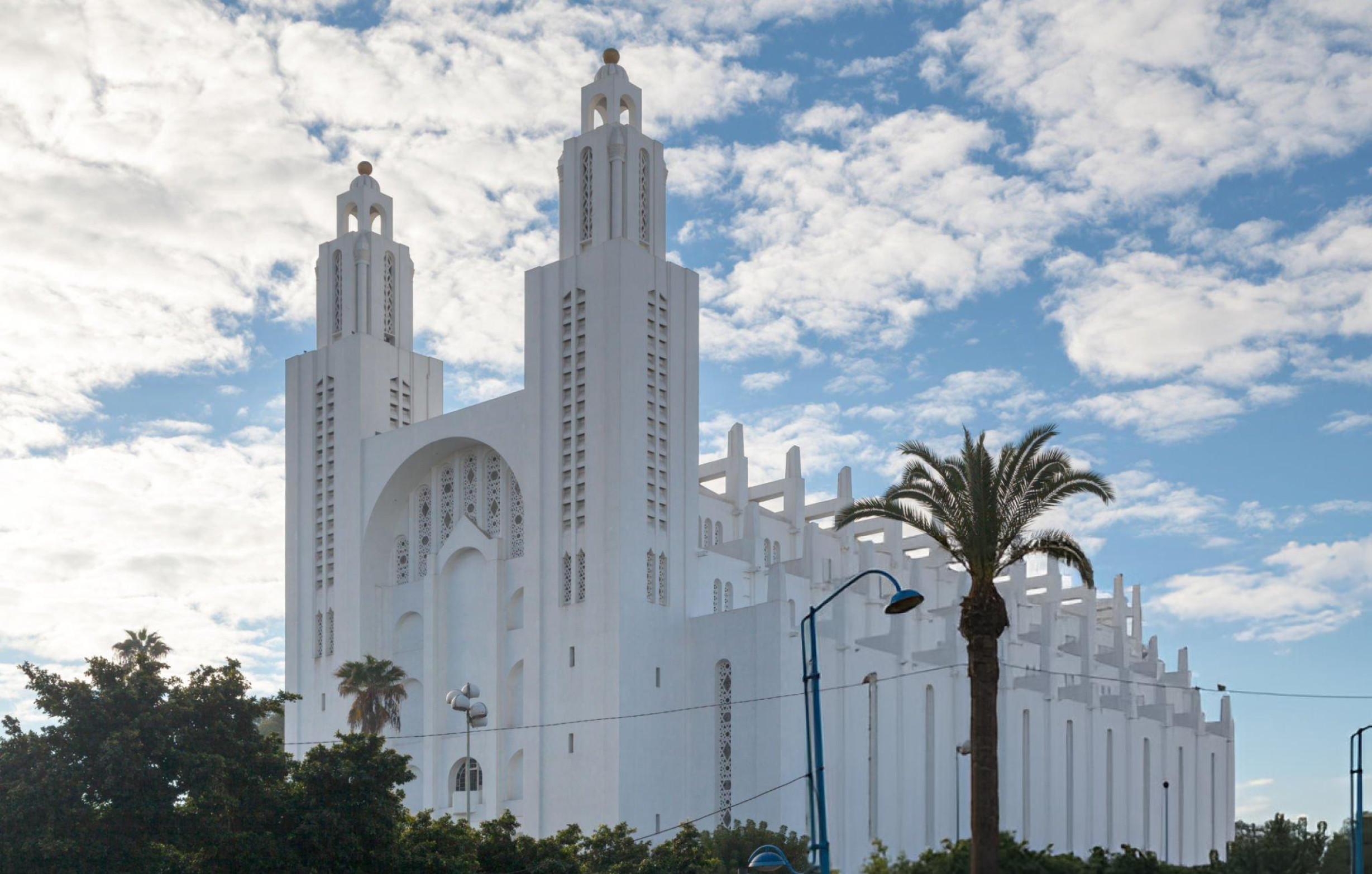 The impressive white facade of the Casablanca Cathedral (Sacré-Cœur) standing tall against a clear blue sky.