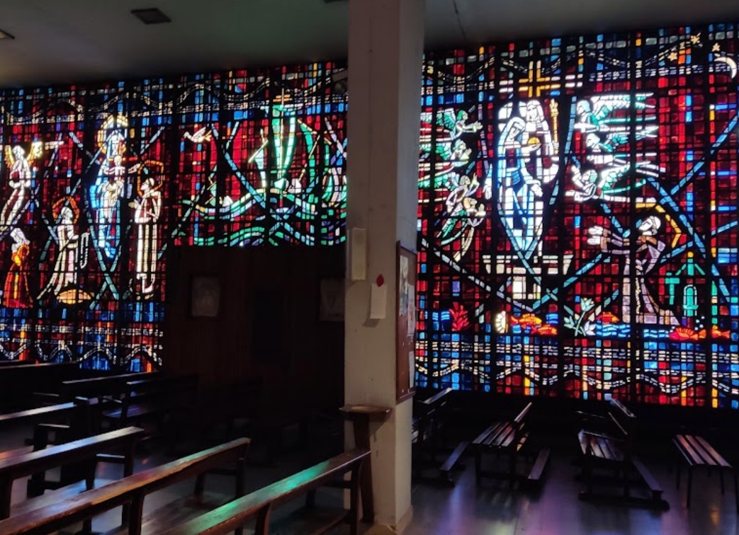 Vibrant light streaming through the massive, abstract stained-glass windows of the Church of Notre Dame of Lourdes
